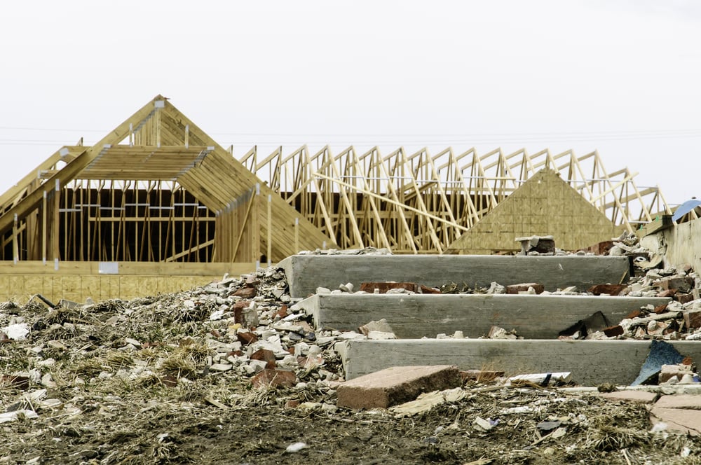 Contrast in tornado recovery Foreground of abandonment with broken debris by concrete steps of blasted foundation in contrast with reconstruction of single-family house across the street